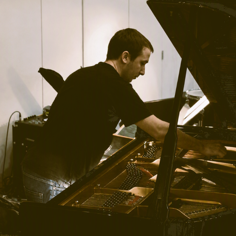 Accordeur de piano ajustant une cheville à l'aide d'une clé d'accord lors de l'accord d'un piano à queue.